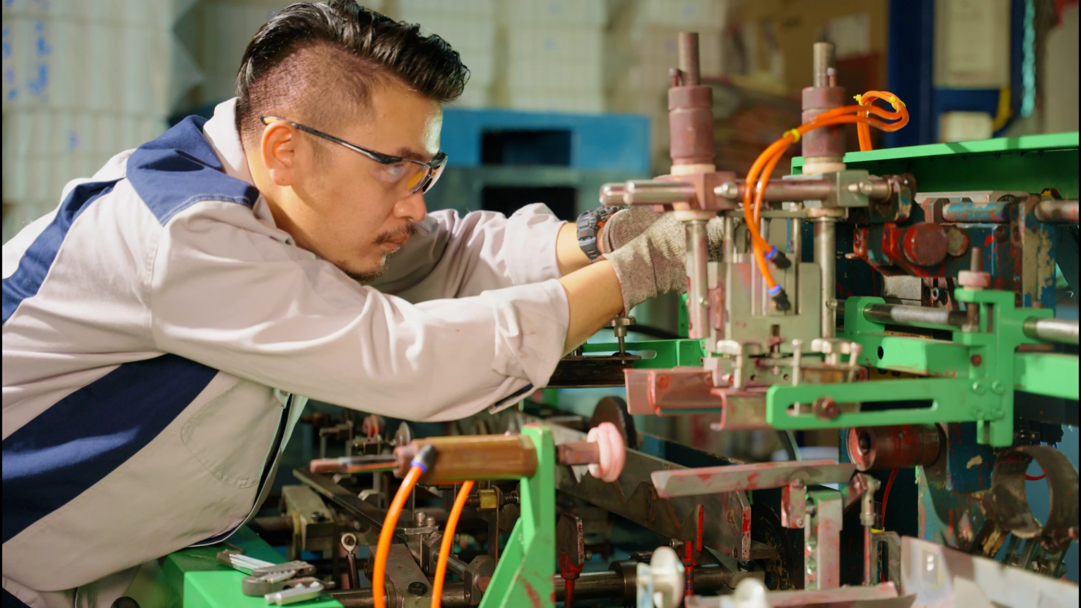 Un trabajador calificado realiza ajustes a una máquina en una fábrica, lo que refleja el trabajo realizado en empleos técnicos.