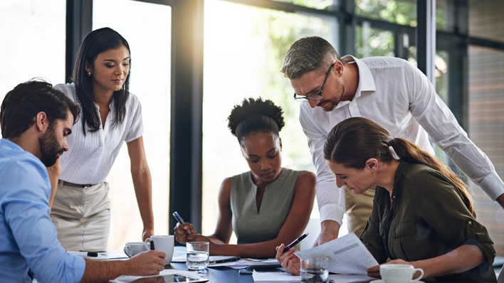 Un equipo hace una reseña de los datos de MPact Advantage en una mesa de conferencias para fortalecer su estrategia y planificación de fuerza laboral.