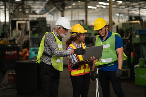 Trabajadores del equipo técnico discutiendo alrededor de una computadora portátil